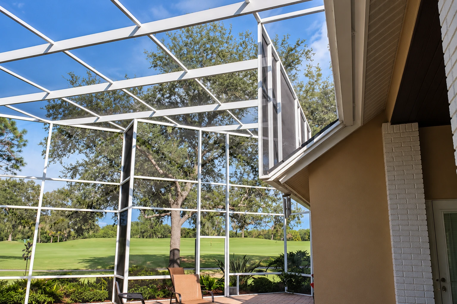 Enclosed patio with white-framed screens and a peaked roof, overlooking a green lawn and trees.