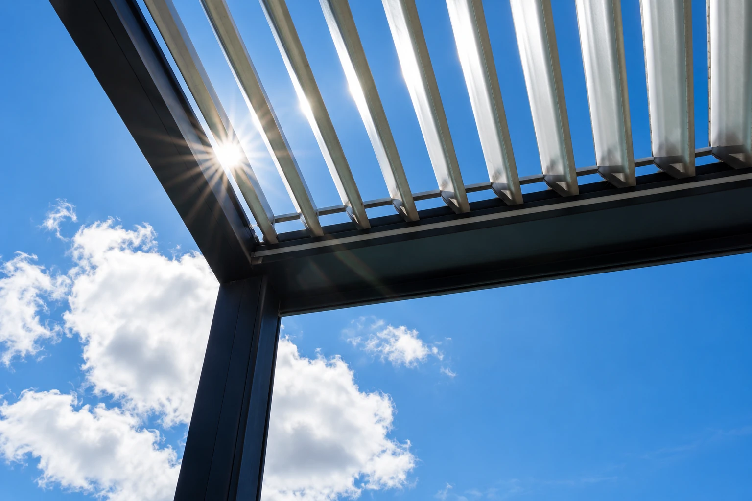 Close-up view beneath a slatted sunroom roof, with sunlight shining through against a blue sky.